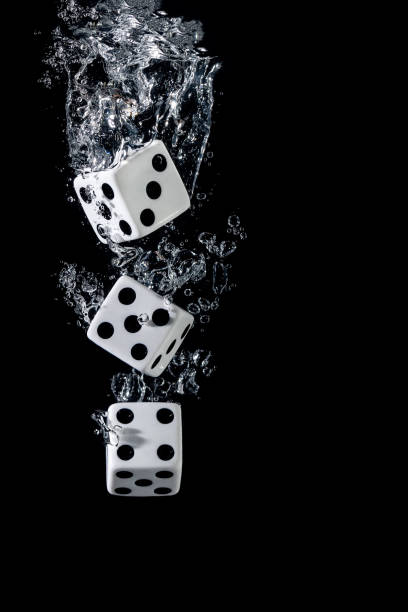 Dices sinking in water with bubbles on black background stock photo