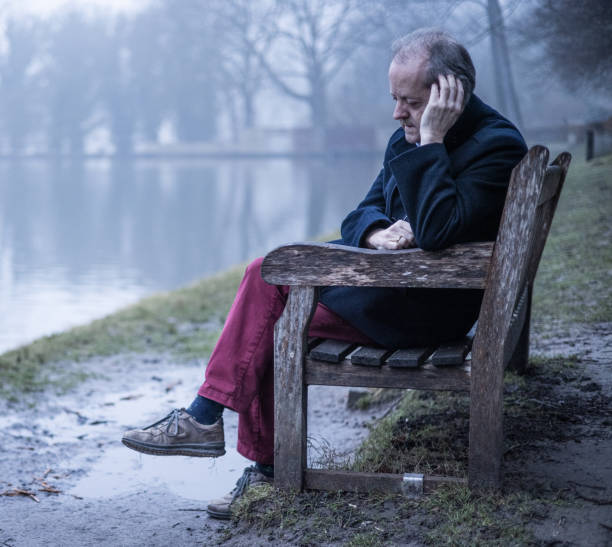 istock Leaning elbow on the park bench, a middle aged man alone in misty forest, lonely and abandoned in gloomy atmospheric mood 1305963615