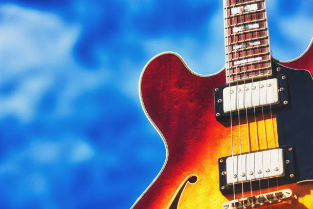 istock Brightly colored semi-acoustic electric guitar against a lightly cloudy sky 1305963716