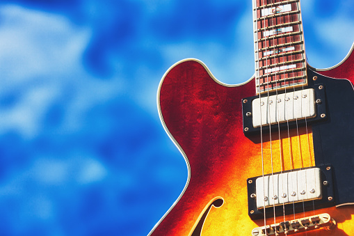 Electric guitar against an inspiring sky. This type of guitar, based on a 1950s design, is produced by many manufacturers and has become generic. It is used in every conceivable popular music style.