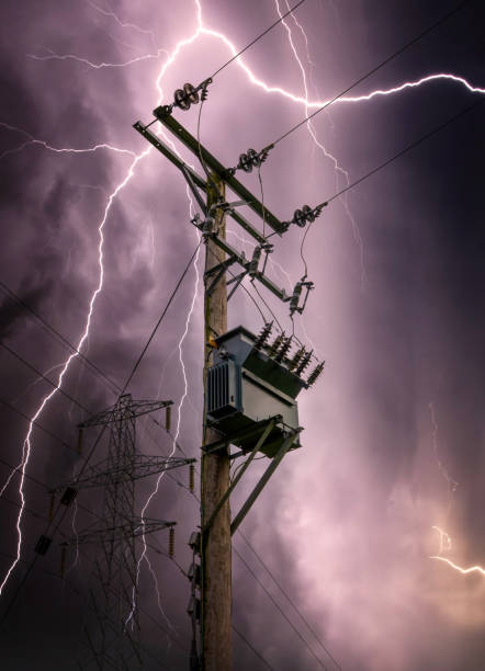 Bright lightning bolts striking electric power pylon tower cables and sub station strike. Electricity discharge cloud to ground storm with transformer on wooden telegraph pole silhouette against sky. Incredibly bright sheet lightning bolts striking electric power pylon tower cables and sub station strike. Electricity discharge cloud to ground storm with transformer on wooden telegraph pole silhouette against sky. Sheet lightening across the sky. lightning tower stock pictures, royalty-free photos & images