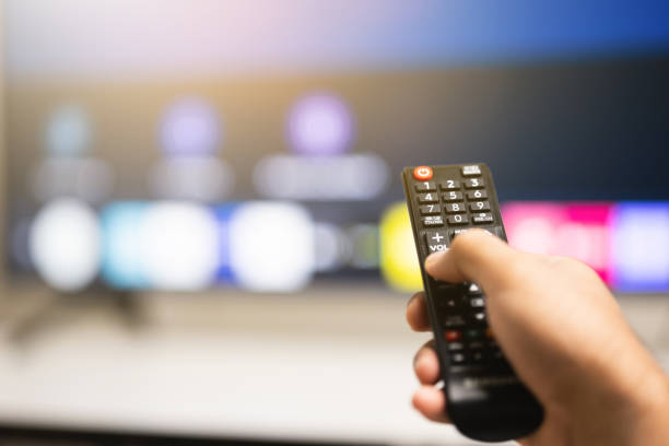 istock Close up male hand holding remote control pointing to change the programme television. 1305968556