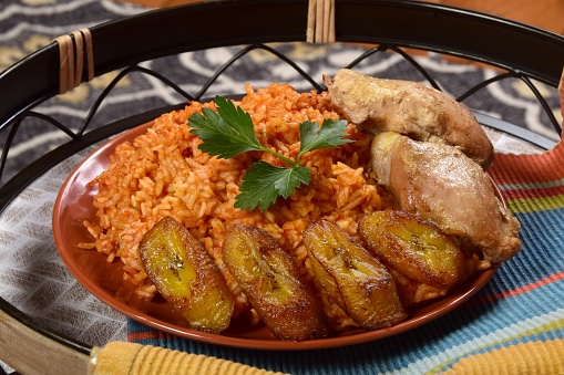 Traditional West African Jollof rice with chicken, seasoned with peppers, tomatoes and ginger and served with fried sweet plantains.