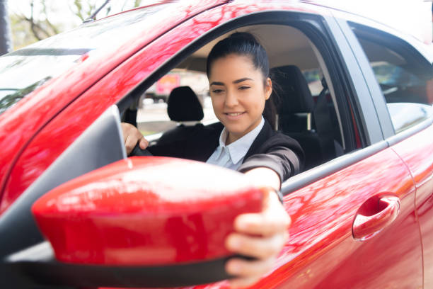 istock Woman moving rear view wing mirror in car. 1305969553