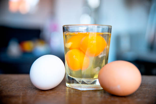 Eggs protein diet Row Eggs in the glass by the white and yellow uncooked egg in the kitchen brown table. close up Raw Egg stock pictures, royalty-free photos & images