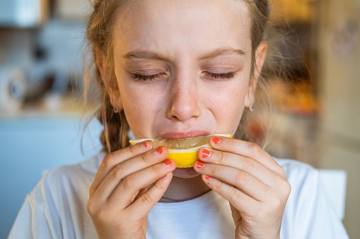 Girl eating sour lemon