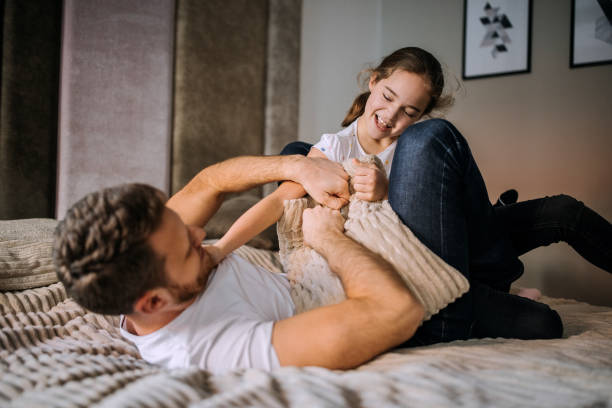 istock Father and daughter playing on a bedroom bed 1305975399