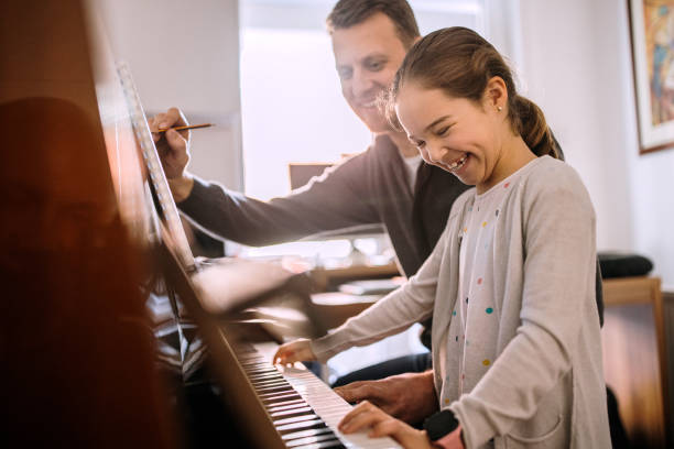 istock Father and daughter having fun while playing piano 1305976322