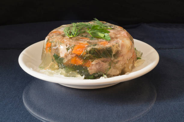 Aspic meat in a white plate on the table. Food on a black background