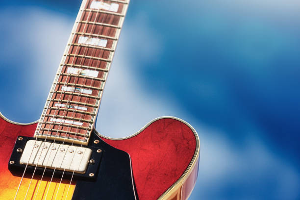 istock Brightly colored semi-acoustic electric guitar against a lightly cloudy sky 1305977652