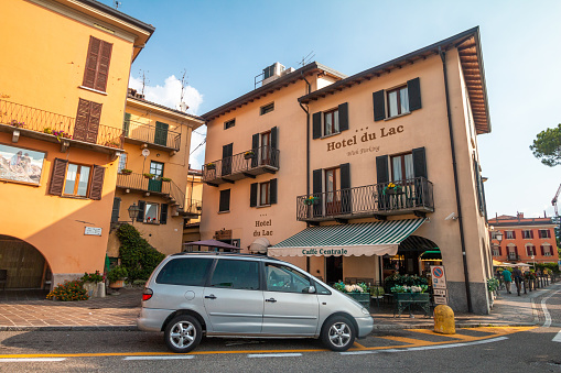 Hotel du Lac in Menaggio, Italy, with a car parked in front and people walking on the sidewalk