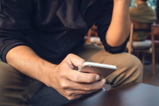 istock closeup man using mobile smart phone in coffee shop with soft-focus and over light in the background 1305978120