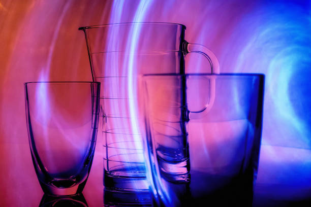 Still life - empty yellow glass on vibrant multicoloured neon background.