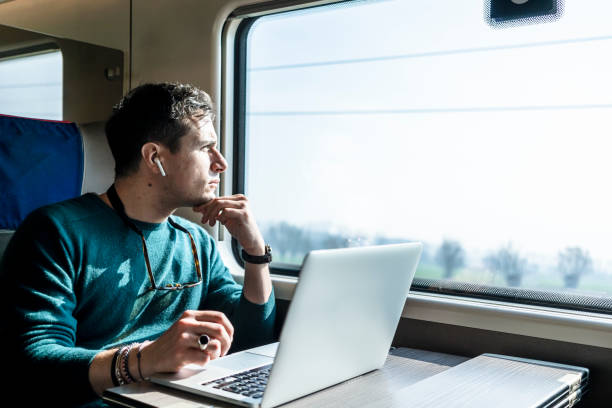 istock Businessman working on train with laptop 1305980498