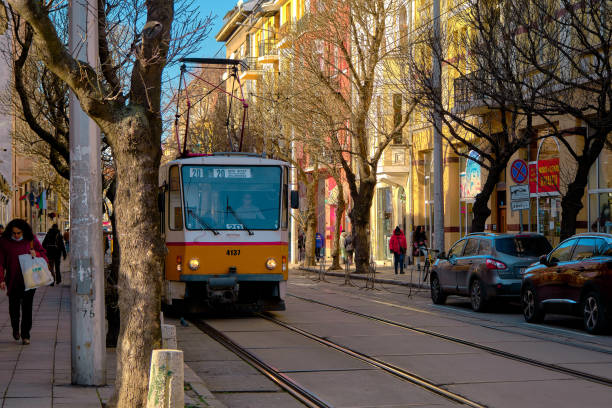 Old yellow tram near the bazaar called as women bazaar on the cobblestone and people walking around and cars parking on the street.