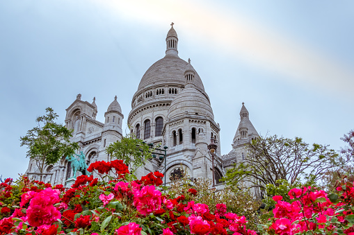 France. Cloudy evening near Sacre Coeur  Cathedral in Paris. Flowerbed with red roses in the foreground