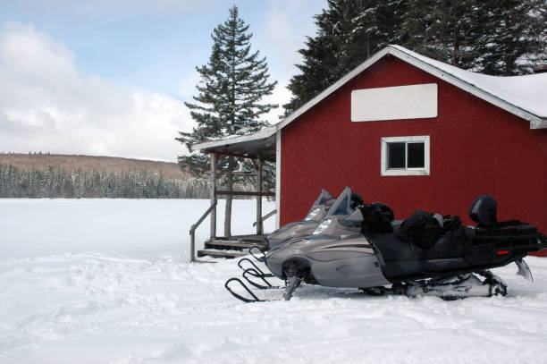 Snowmobiling Snowmobiles parked outside a tiny lakeside cabin. Snowmobiling stock pictures, royalty-free photos & images