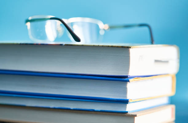 An eyeglasses sitting on top of colorful books.