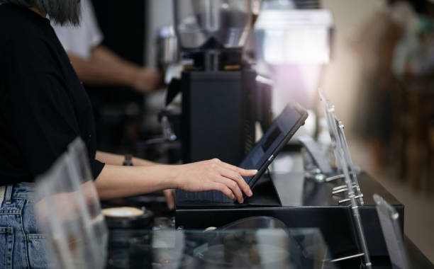 business, finance and technology Side view of a young woman touching on the digital tablet to recive order from customer in coffee shop. point of sale stock pictures, royalty-free photos & images