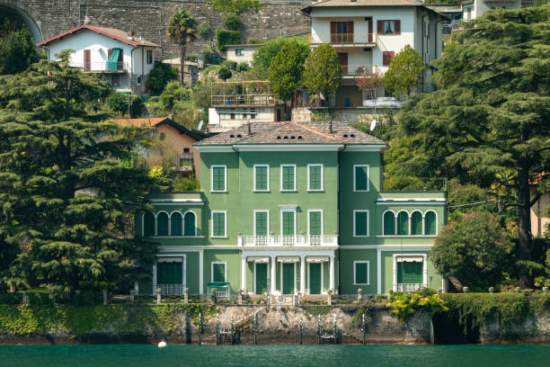 An old house on the edge of a lake Como with the Alps in the background Italy
