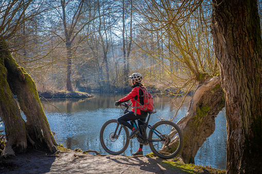 Senior woman on electric Mountain bike at river in spring