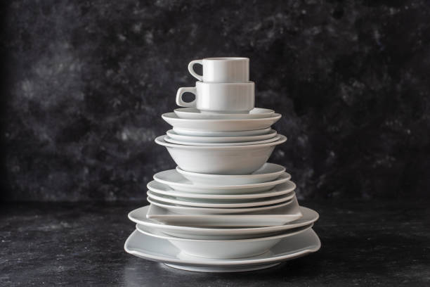 Many white empty plate and cup on black background, close up