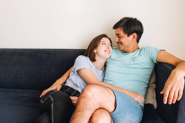 istock Young couple embracing on the sofa looking at each other and smiling 1305992019