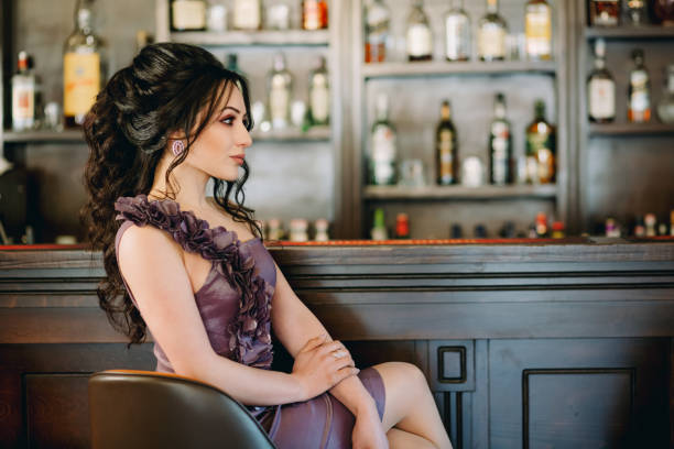 istock Cute young woman sitting, holding hands and posing in pub 1305993412
