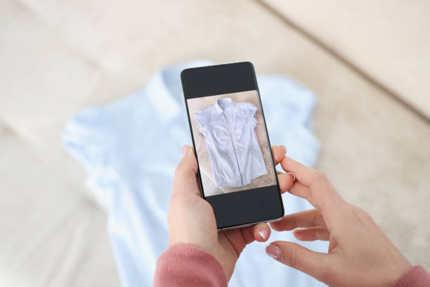 la main femelle retient le smartphone et fait des photos de la chemise bleue - second hand photos et images de collection