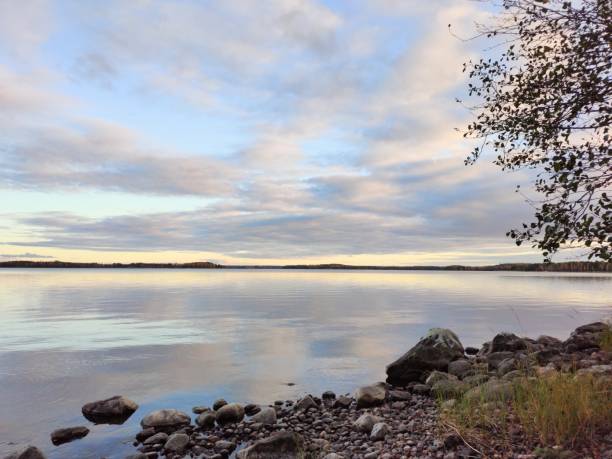 Sunset pastel colors reflecting from the clouds.  Lake is calm and mirrors the sky.