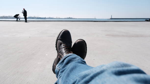 Istanbul bosphorus and a man foot wearing winter boots and extends to sea of marmara and people taking photo ​haydarpasa train station and lighthous