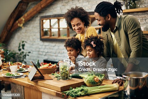 istock Happy African American family preparing healthy food in the kitchen. 1306001320