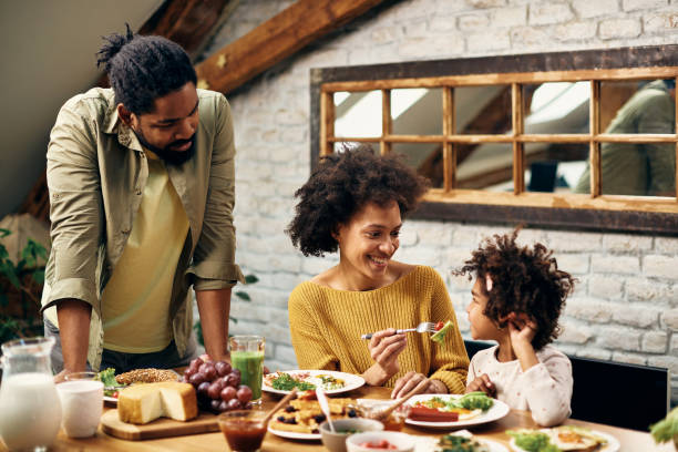 istock Happy black parents with daughter enjoying while having meal at dining table. 1306001370