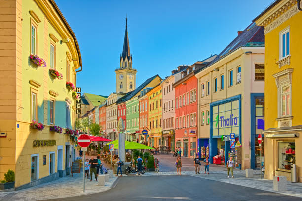 Villach, Austria: View of the main street with colorful historical houses and the main square in a small Austrian city. People are walking along the street with shops, bars, and restaurant stock photo
