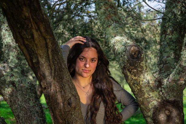 istock attractive girl with long hair, under a tree looks at camera 1306004591