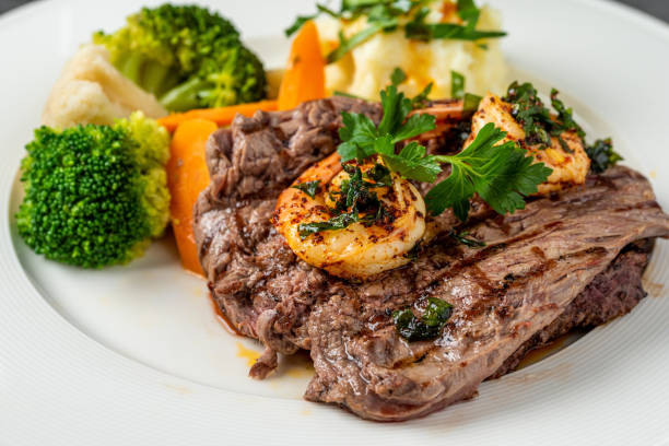 delicious juicy grilled steak and shrimp with grilled broccoli and cauliflower.  surf and turf style. - surf and turf prepared shrimp seafood steak imagens e fotografias de stock