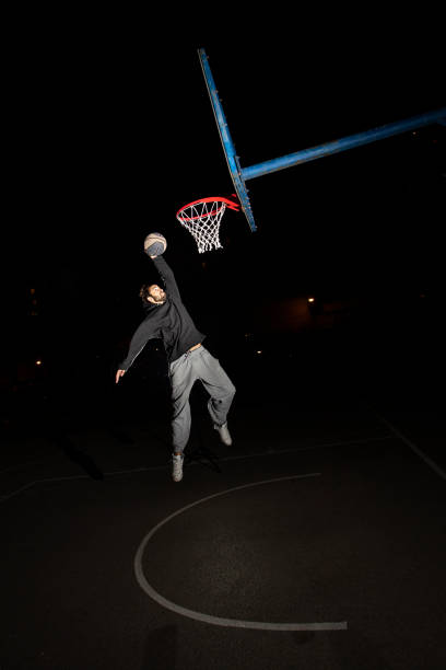 istock Young man playing basketball at night 1306007456