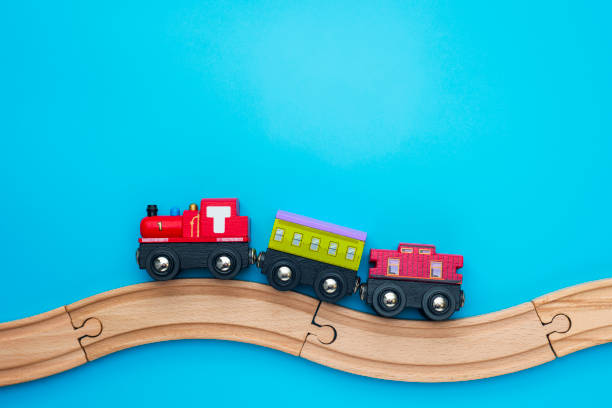 Toys background with copy space. Kids toy train with two carriages on wooden railway  on blue background with copy space for text. Toys background with copy space. Kids toy train with two carriages on wooden railway  on blue background with copy space for text. miniature train stock pictures, royalty-free photos & images