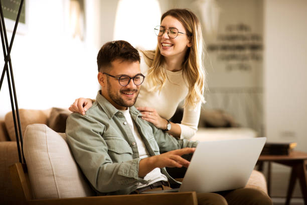 istock Smiling couple relaxing at home and working on laptop 1306008865