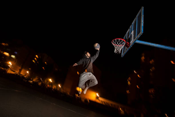 istock Young man playing basketball at night 1306009455