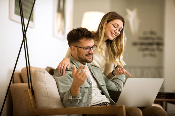 istock Smiling couple relaxing at home and working on laptop 1306009569