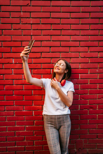 istock Woman making selfie in front of brick wall 1306009782