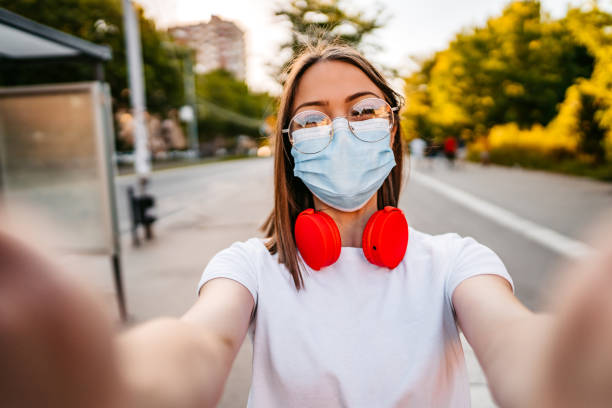 istock Woman with face mask making selfie on street 1306009896