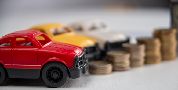rise in car prices. model cars and piles of coins