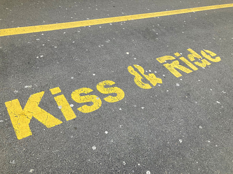 Yellow Kiss and Ride inscription painted on asphalt at the drop off parking station in Zug, Switzerland