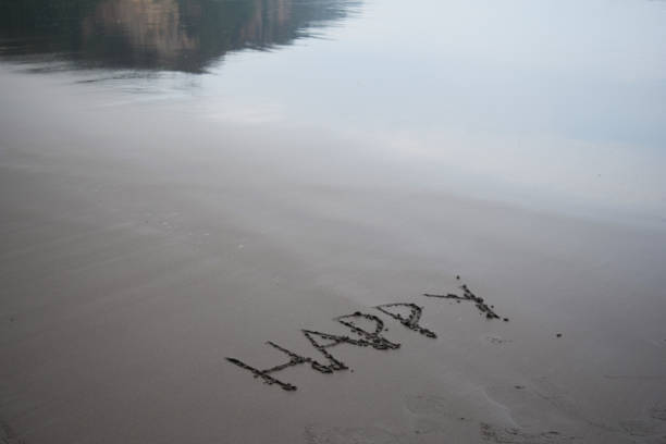 pisanie słowa "szczęśliwy" na czarnej piaszczystej plaży - happy land zdjęcia i obrazy z banku zdjęć