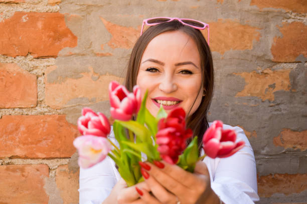 istock Woman next to a brick wall holding tulips 1306019565