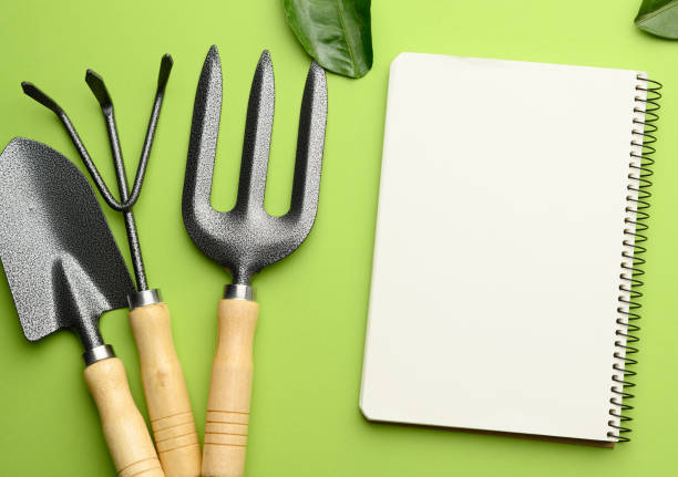 istock open notebook with blank white sheets and various gardening tools with wooden handles on green background, flat lay 1306021171