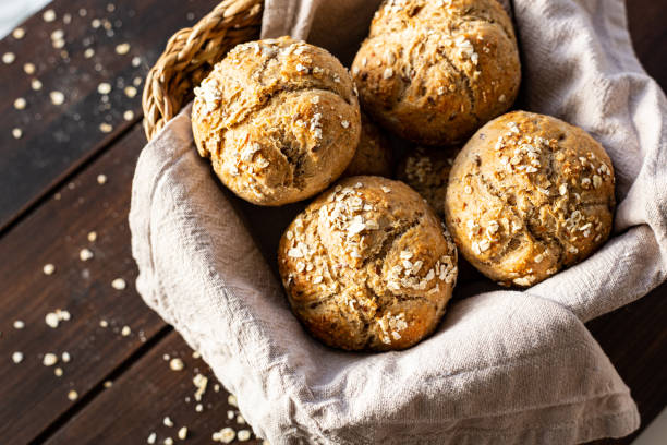 Breakfast rolls in a bread basket on wooden plank from above