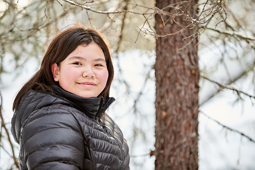 Portrait of beautiful girl in warm jacket standing outside looking at camera and smiling